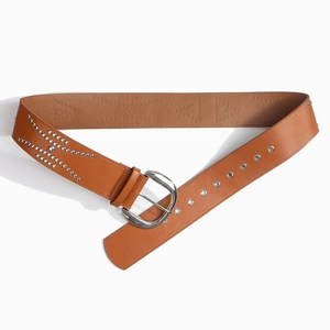 Close-up of brown leather wide belt featuring silver metal rivets and geometric eyelet details