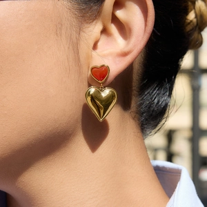 Boucles d'oreilles cœur en or et émail rouge sur modèle sous lumière naturelle