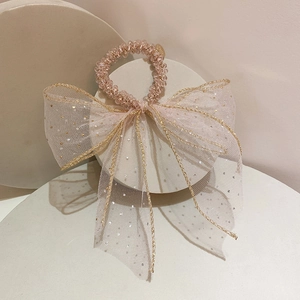 Pink telephone cord hair tie with transparent mesh bow and gold polka dots on display