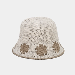 Detailed view of handmade crochet flower patterns on a beige knit bucket sun hat