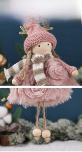 Detail of a pink plush angel ornament with sequin antlers and knit hat on a blue background