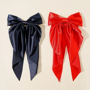 Detail of red and navy oversized satin bow hair clips with long elegant streamers