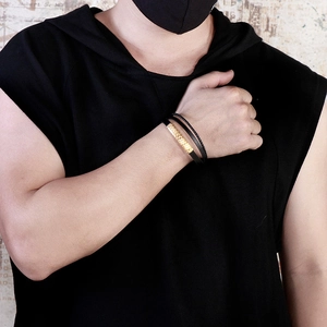 Detail of men's layered leather bracelet with a textured gold geometric metal buckle