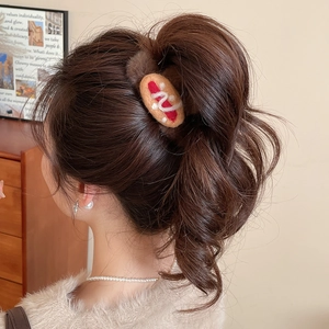 Detail view of a creative plush hot dog shaped hair claw clip on a woman's ponytail