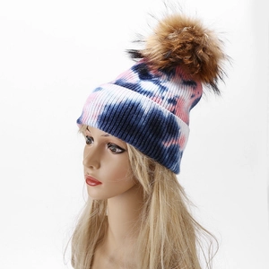 Close-up of pink and blue tie-dye knit beanie with fluffy brown faux fur pom pom