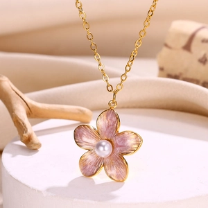 Close-up of pink enamel flower pendant with a central pearl on a golden chain necklace