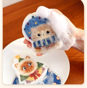 Close-up of hand squeezing blue cat sponge creating rich foam for dishwashing