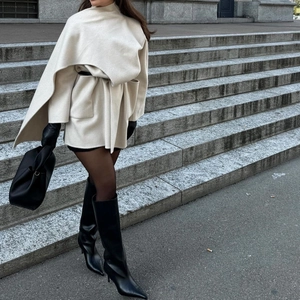 Minimalist beige wool blend shawl collar coat styled with black leather boots and gloves