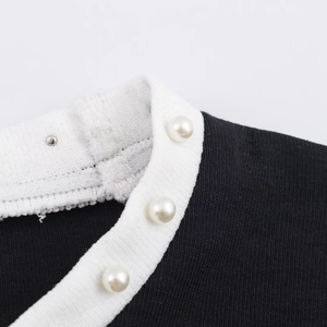 Dettaglio dello scollo della maglietta con perle finte decorative e bordo bianco a contrasto