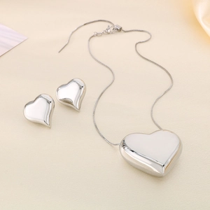 Gros plan sur le collier à pendentif cœur argenté et les boucles d'oreilles assorties