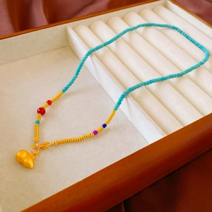 Détail d'un collier de perles avec pendentif papillon doré et perles colorées en boîte à bijoux