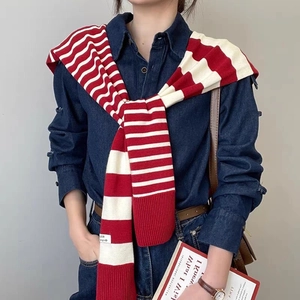 Detailed view of a red and white striped knit shawl draped over shoulders with small tag