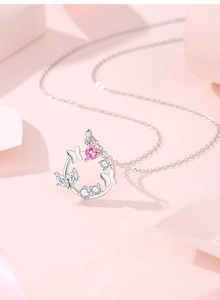 Macro detail of S925 silver necklace featuring a pink heart stone and butterfly wreath pendant