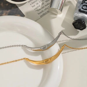 French vintage smile pendant necklace in gold and silver finish on white ceramic tray