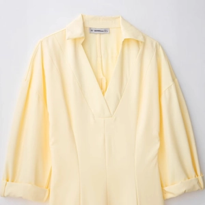 Elegante abito a camicia giallo chiaro con revers e scollo a V su sfondo bianco pulito
