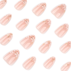 Faux ongles amande courts avec motifs de fleurs blanches et feuille d'or sur base nude
