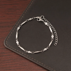 Detail of silver stainless steel chain bracelet with textured links on leather mat