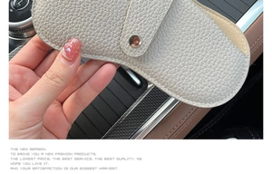 Close-up of grey pebble grain leather glasses pouch with silver snap button inside a car