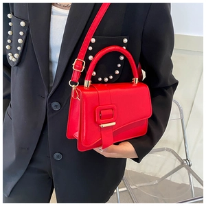 Macro shot of red leather crossbody bag with gold hardware and pearl suit details