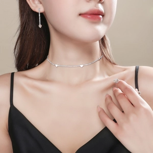 Elegant silver heart necklace and earrings set with rhinestones on a female model