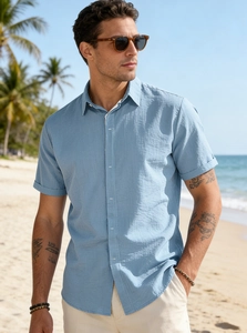 Close-up of light blue short sleeve linen shirt texture with button detail on beach