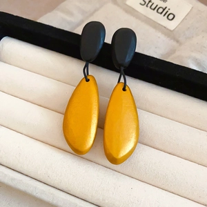 Macro view of teardrop wooden drop earrings in yellow and black on a jewelry display