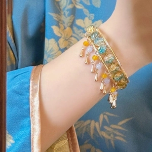 Macro detail of Chinese style beaded bracelet with golden wire wrap and tassel charms