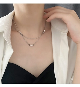 Close-up of a double-layered silver beaded necklace worn on a elegant female model