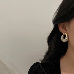 Élégantes boucles d'oreilles créoles dorées en U avec perles blanches sur un modèle