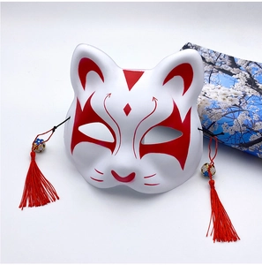 Detail of hand-painted Japanese fox mask with red tassels and decorative bells