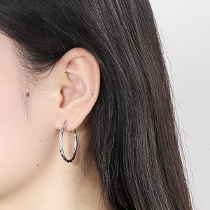 Macro shot of 30mm twisted rope texture hoop earrings in polished silver stainless steel