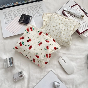 Détail de pochettes en toile à fleurs et cerises sur un fond de tissu blanc élégant
