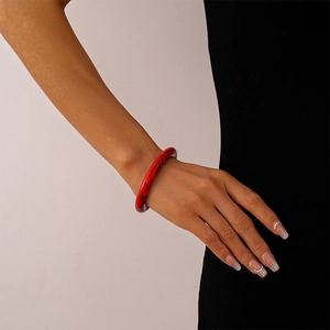 Detail of red marble texture acrylic cuff bracelet worn by a model in an elegant setting