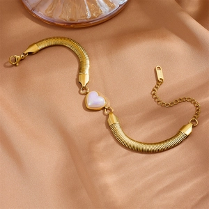 Golden 6mm snake chain bracelet with heart-shaped pearl pendant on brown silk fabric