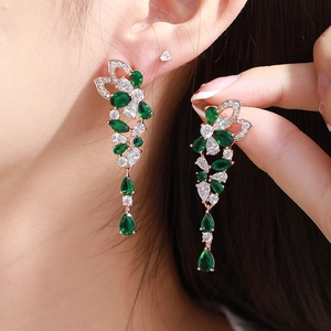 Close-up of elegant emerald green teardrop earrings worn by a model for formal events