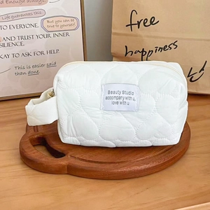 Detail of white quilted heart pattern makeup bag on a decorative wooden tray