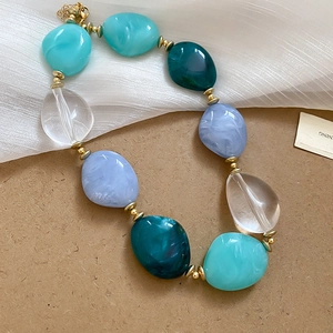 Detail of blue acrylic oval beaded necklace with gold spacers and lobster clasp