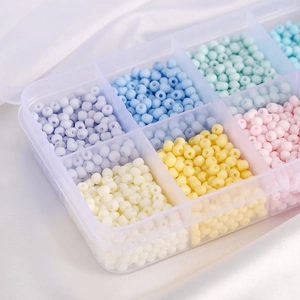 Macro shot of macaroon glass seed beads set in clear plastic organizer on white silk
