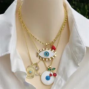 Layered 18K gold-plated necklace with cherry and evil eye pendants on a mannequin