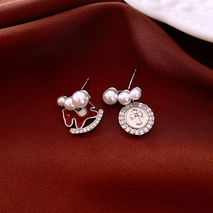 Detail of asymmetrical red and cross-pendant earrings with pearls on red silk