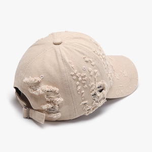 Beige washed cotton baseball cap with distressed ripped holes and metal buckle strap