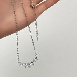 Detailed macro view of a silver smiley necklace with seven sparkling cubic zirconia stones