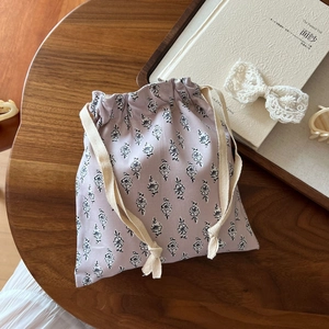Detailed shot of floral cotton drawstring bag on wooden table with elegant accessories