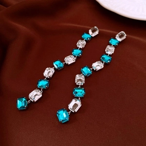 Detail of silver long tassel earrings with blue and clear emerald-cut crystals