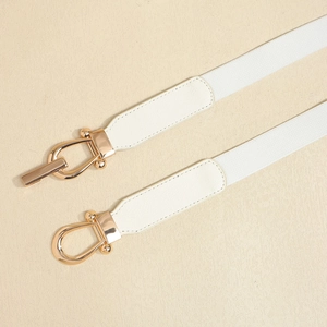 Close-up of white elastic waist belt with gold horse-bit buckle and leather stitching