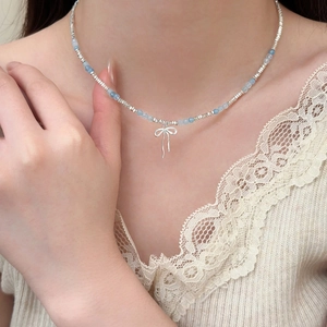 Close-up of a bow pendant necklace with irregular silver beads and light blue accents
