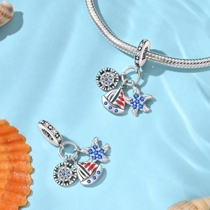 Macro detail of nautical silver sailboat, ship wheel and blue starfish charms for bracelets