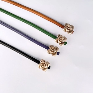 Detail of four colorful leather belts featuring elegant golden rose shaped metal buckles