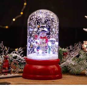Dettaglio di palla di neve con pupazzo di neve e luci LED su un tavolo in legno