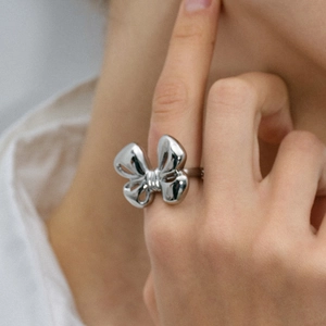 Detailed view of a silver bow knot ring on a finger with a polished metal finish